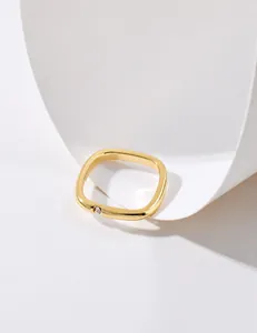 Close-up of golden cushion-cut ring with a small sparkling stone inlay on white background