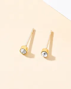 Close-up of minimalist gold stud earrings with round brilliant-cut clear cubic zirconia