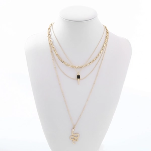 Elegante collana dorata a più strati con pendente a serpente esposta su un manichino a busto bianco