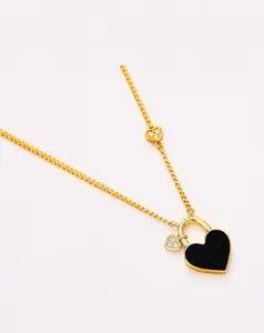 Detailed view of golden heart lock pendant with black enamel and zircon accents