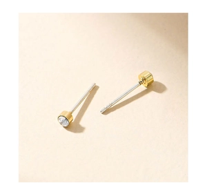 Detail of S925 silver needle stud with gold rim and sparkling clear round zircon