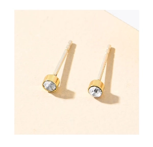 Macro shot of minimalist gold S925 earrings with a single round-cut white gemstone inlay