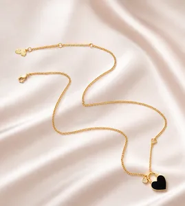 Detail of gold chain necklace with black heart pendant and butterfly extension clasp