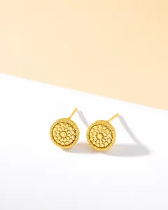 Detail of round golden stud earrings with fine textured granule dots in boho style