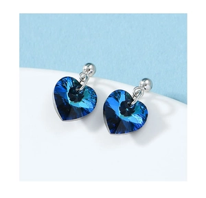 Macro shot of silver heart earrings featuring deep blue Austrian star-cut crystals