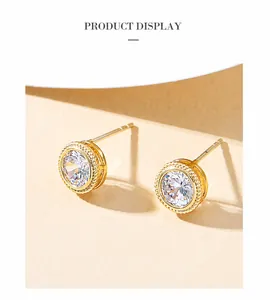 Detail of gold-plated geometric earrings with large zircon center stones and beaded texture
