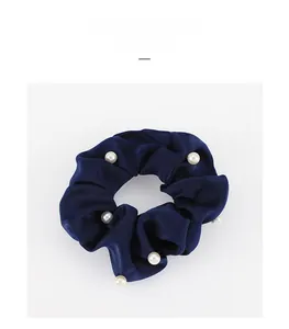 Détail macro du chouchou en satin bleu marine orné d'élégantes perles blanches nacrées