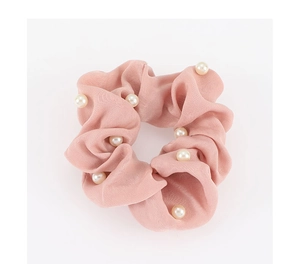 Détail de chouchou en satin rose poudré avec perles blanches et texture plissée