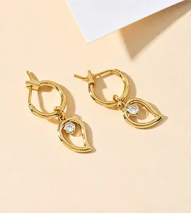 Detailed view of gold-plated drop earrings with teardrop hollow and clear zircon inlay