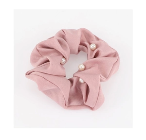 Détails d'un chouchou en satin rose orné d'élégantes perles blanches sur le tissu