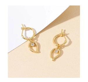 Detail of gold dangle earrings with hollow teardrop pendants and sparkling cubic zirconia