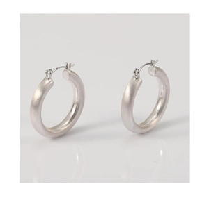 Vue détaillée des boucles d'oreilles créoles argentées mates avec texture brossée