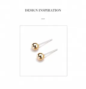 Detailed close-up of geometric golden ball stud earrings with a polished mirror finish