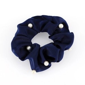 Chouchou en satin bleu foncé orné de perles blanches sur fond blanc
