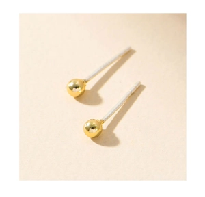 Macro shot of minimalist gold ball stud earrings with S925 silver pins on beige background