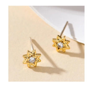 Macro shot of gold-plated star earrings with bright zircon inlay and hollow design