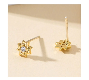 Macro shot of gold hexagram stud earrings with sparkling round zircon center
