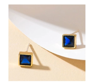 Detail view of square blue gemstones set in elegant gold-plated S925 silver stud earrings