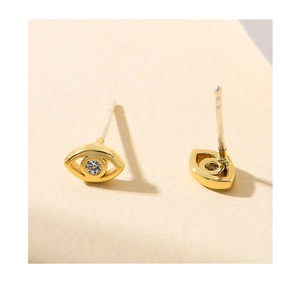 Close-up of gold-plated evil eye stud earrings featuring clear cubic zirconia centers
