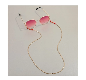 Vue détaillée d'une chaîne de lunettes dorée avec perles rouges sur des lunettes