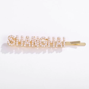 Goldene Haarklammer mit perlenbesetztem SHANGHAI Schriftzug auf weißem Hintergrund