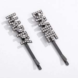 Vue détaillée de deux barrettes noires avec les lettres HAPPY et DRINK en strass