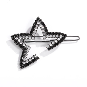 Macro detail of star-shaped hair clip with black and silver rhinestones on dark metal