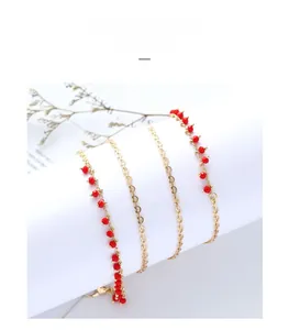 Detailed macro view of golden metal chain necklace featuring vibrant red round bead accents
