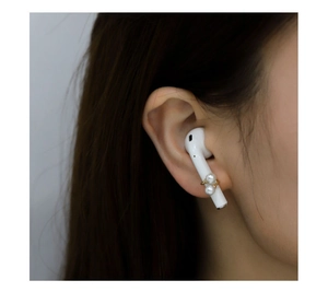Vue détaillée des clips de perles dorées sur écouteurs sans fil montrant le style élégant
