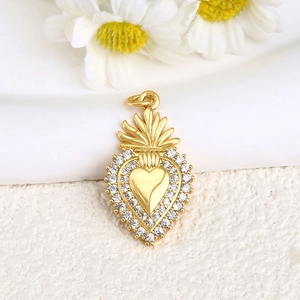 Golden sacred heart pendant with small white rhinestones on a white floral background