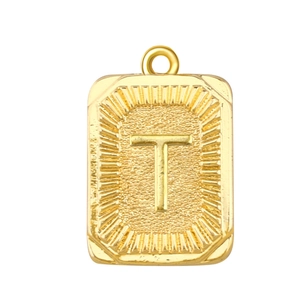 Detalle de un colgante rectangular dorado con la letra T y un patrón de rayos de sol