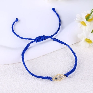Detailed close-up of blue braided Hamsa Hand bracelet with evil eye on white background