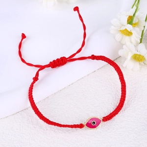 Detailed view of handmade red braided cord bracelet with gold-plated evil eye charm