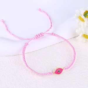 Detail of pink woven bracelet featuring a pink Evil Eye palm charm with adjustable closure