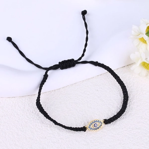 Detailed view of hand-woven black cord bracelet with golden Evil Eye pendant and adjustable knot
