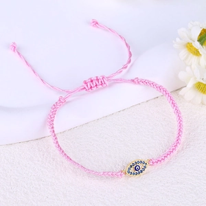 Detailed view of adjustable pink braided Evil Eye bracelet with sparkling blue zircon inlay