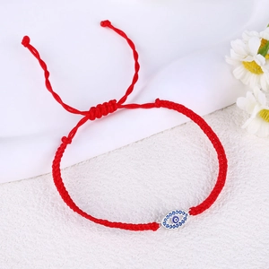 Detail of red braided evil eye bracelet with blue zircon inlay and adjustable slide knot