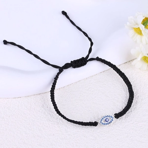 Detail view of handmade black braided rope bracelet with blue evil eye charm and slide knot