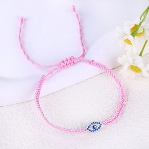 Detailed macro view of pink braided evil eye bracelet with blue marquise pendant
