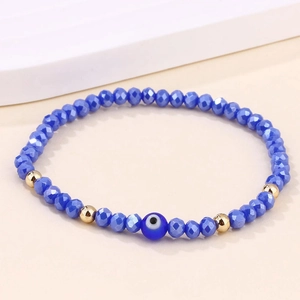 Vue macro d'un bracelet œil porte-bonheur bleu fait main avec perles dorées et cordon