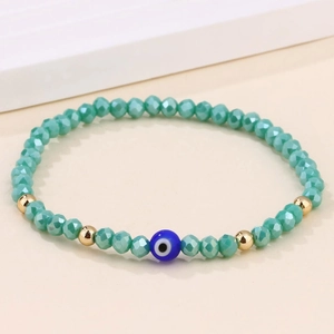 Détail macro du bracelet perlé turquoise avec œil bleu et perles d'espacement dorées