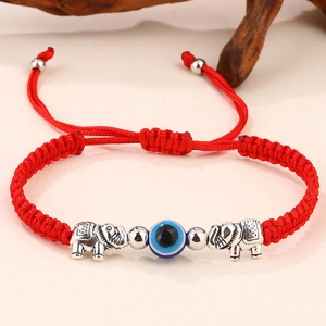 Dettaglio del bracciale intrecciato rosso con ciondoli elefante e perla occhio blu