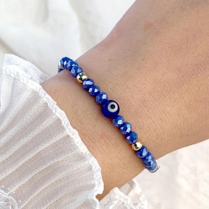 Gros plan d'un bracelet en perles de cristal bleu avec charme mauvais œil au poignet