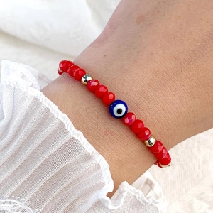 Détail des bracelets œil protecteur en cristal rouge avec perles dorées au poignet