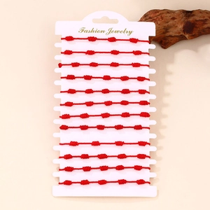 Dettaglio di un set di 12 braccialetti in corda rossa intrecciata su un espositore gioielli