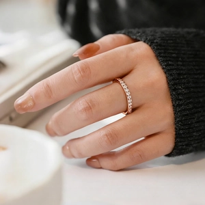 Detailed view of a rose gold full diamond band ring worn on a finger in a cozy setting
