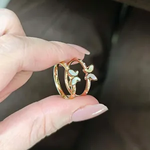 Detailopname van vlinderringen in goud en roségoud met wit schelpmateriaal
