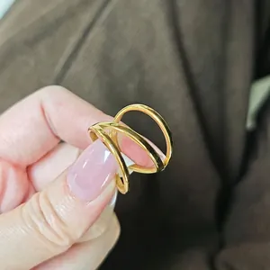 Close-up of a multi-layer 18k gold minimalist ring with a polished geometric crossover design