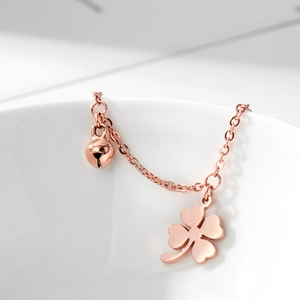 Minimalistisches Fußkettchen aus 18k Roségold mit Blume und Glocke auf weißem Keramik