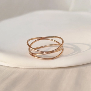 Primer plano de un anillo multicapa de acero de titanio oro rosa con diseño de líneas cruzadas